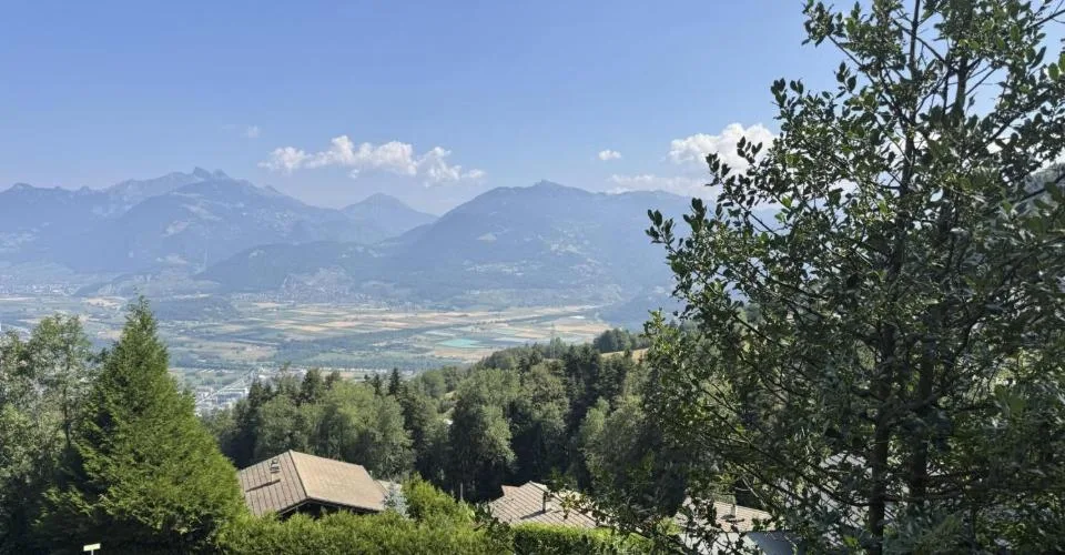 Chalet en rondins d'épicéa dans un écrin de verdure, avec vue sur la plaine du Rhône