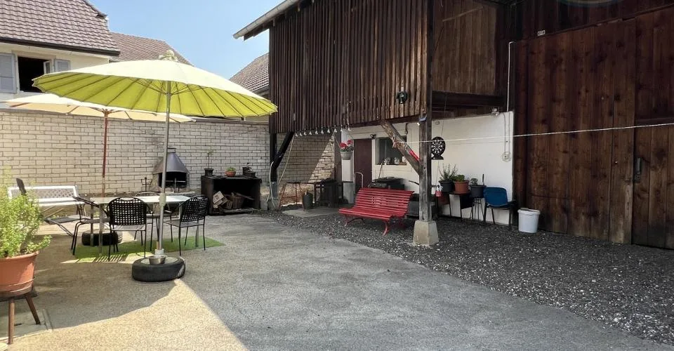 Maison villageoise avec une grande grange et un grand jardin.