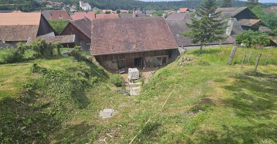 Maison villageoise avec une grande grange et un grand jardin.
