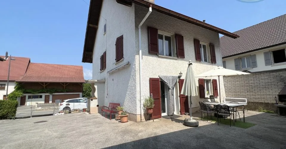 Maison villageoise avec une grande grange et un grand jardin.
