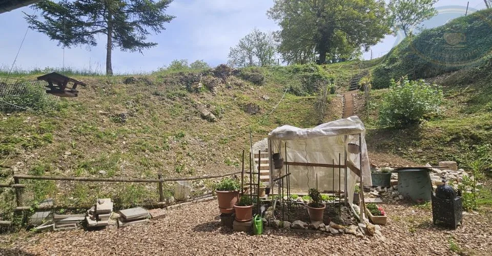 Maison villageoise avec une grande grange et un grand jardin.