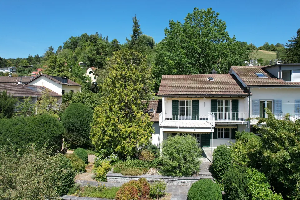 einseitig angebautes Einfamilienhaus mit separatem Garagengebäude und parkähnlicher Gartenanlage